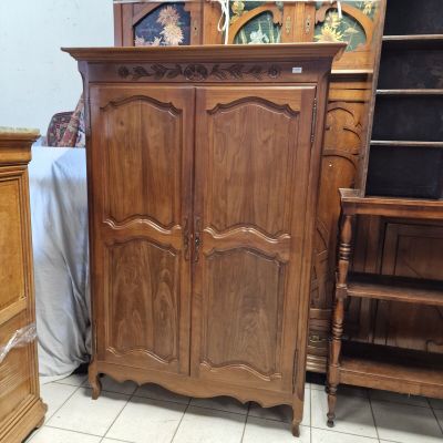 une armoire en bois placée dans un coin de la pièce, à côté d'un lit
