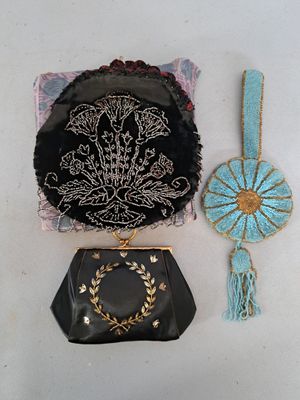 un sac à main noir et un sac à main bleu et doré posés sur une surface blanche