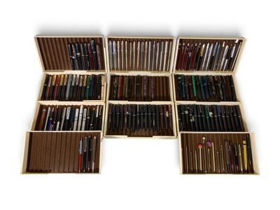 de nombreux stylos dans une boîte en bois posée sur une surface blanche