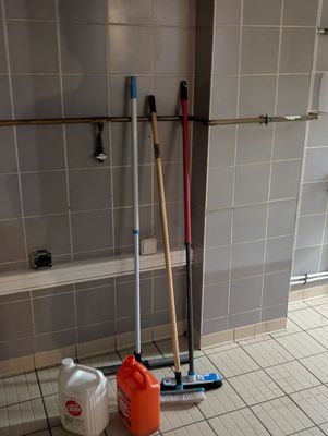 deux balais à franges et un seau posés par terre dans la salle de bains