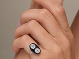 woman ' s hand holding a black and white ring with diamonds