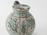 a small vase with a bird on it on a white surface