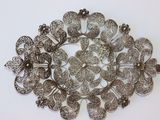 une image représentant une broche en argent posée sur une surface blanche