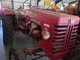 un tracteur rouge garé à l'intérieur d'un bâtiment, dans un garage