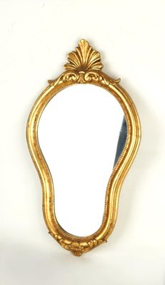 un miroir doré accroché au mur, à côté d'un mur blanc