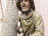 une statue représentant un homme debout à côté d'une tour