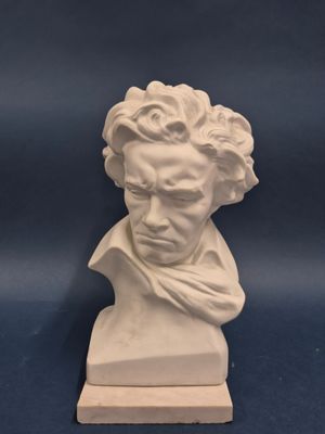 une sculpture blanche représentant la tête d'un homme sur fond bleu