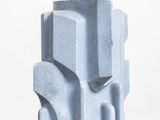 a blue sculpture on a white pedestal on a white surface