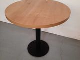 a round wooden table with a black metal base
