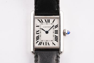 une photo d'une montre argentée avec des chiffres romains, montée sur un bracelet en cuir noir