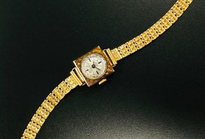 a close up of a gold watch on a black surface