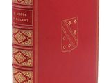 un livre rouge aux bords dorés, avec un emblème doré sur la couverture