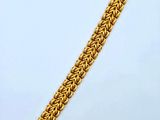 a close up of a gold chain bracelet on a white surface