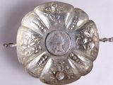 une plaque d'argent ornée d'un motif sur une surface blanche