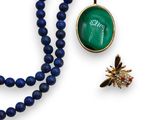 un gros plan d'un collier et d'une broche posés sur une surface blanche