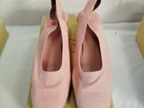 pair of pink shoes sitting on top of a box on a bed