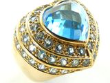 une image représentant une bague en or sertie d'une topaze bleue entourée de cristaux bleus et transparents