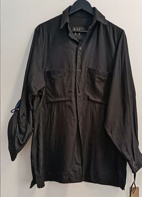 black shirt hanging on a hanger on a wall next to a coat