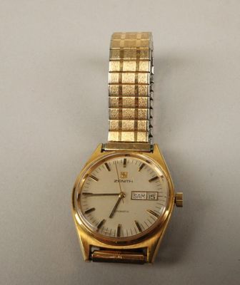 une photo d'une montre en or avec un cadran blanc posée sur une table