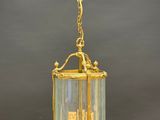a brass and glass hanging light fixture with a castle in the center