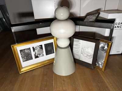 une table sur laquelle se trouvent un vase, des cadres et un tableau