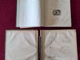 deux livres ouverts posés sur une table recouverte d'un tissu rouge