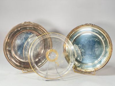 trois assiettes en argent et en or posées sur un présentoir, sur un fond blanc