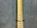 a thermometer on a wooden table with a gray background