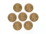 six pièces d'or de tailles et de formes différentes sur une surface blanche