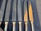 six knives and a knife holder are lined up on a table