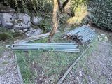 un tas de tuyaux métalliques posé par terre près d'un arbre