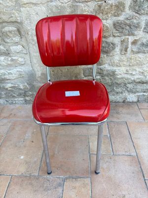 une chaise rouge sur laquelle est posée une étiquette, placée devant un mur de pierre