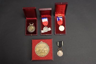 trois médailles et une médaille dans une boîte rouge sur une surface noire