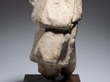 a white sculpture of a head on a wooden base