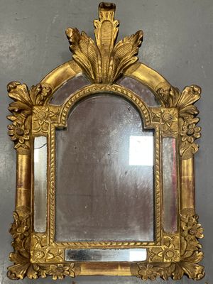 a mirror with a gold frame on the wall