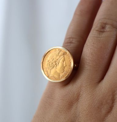someone is holding a gold coin in their hand on a white background