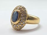 a close up of a gold ring with a blue stone surrounded by white diamonds