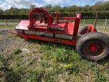 un tracteur rouge garé au milieu d'un champ, près d'une clôture