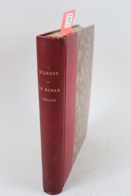un vieux livre à la couverture rouge posé sur une table blanche