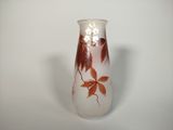 a white vase with red leaves on it sitting on a table