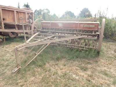 un tracteur garé dans l'herbe, avec une remorque derrière lui