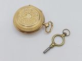 an image of a gold pocket watch and key on a white surface