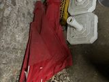 a red umbrella sitting on the ground next to a trash can