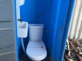 des toilettes situées dans une cabine de toilettes portables bleue équipée d'un lavabo