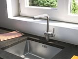 a kitchen sink with a faucet in front of a window