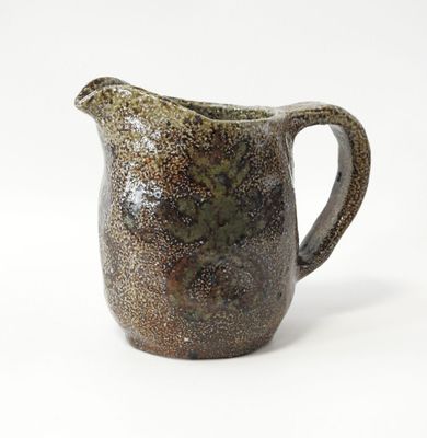 une cruche marron et noire posée sur une surface blanche