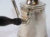 a silver coffee pot with a black handle on a white table