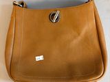 sac à main en cuir beige avec une poignée métallique sur fond blanc
