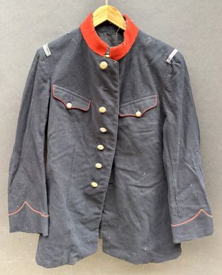 Une veste grise à col rouge est suspendue à un cintre