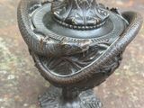 une statue représentant un serpent au sommet d'un vase